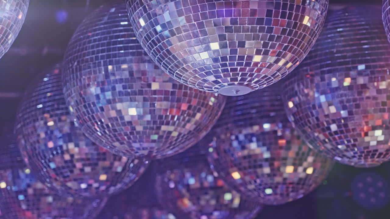 Diverse palle da discoteca che riflettono luci colorate in un ambiente di festa