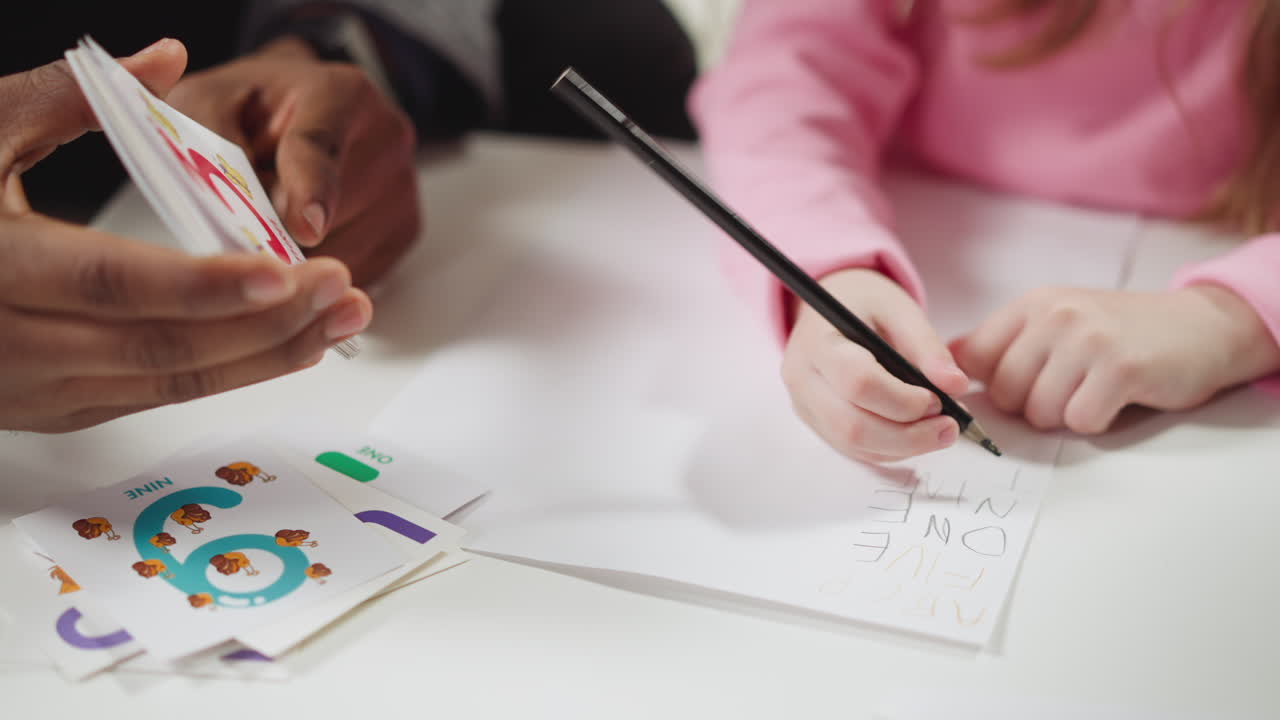 el tutor muestra tarjetas y la chica escribe nombres de dígitos en inglés.