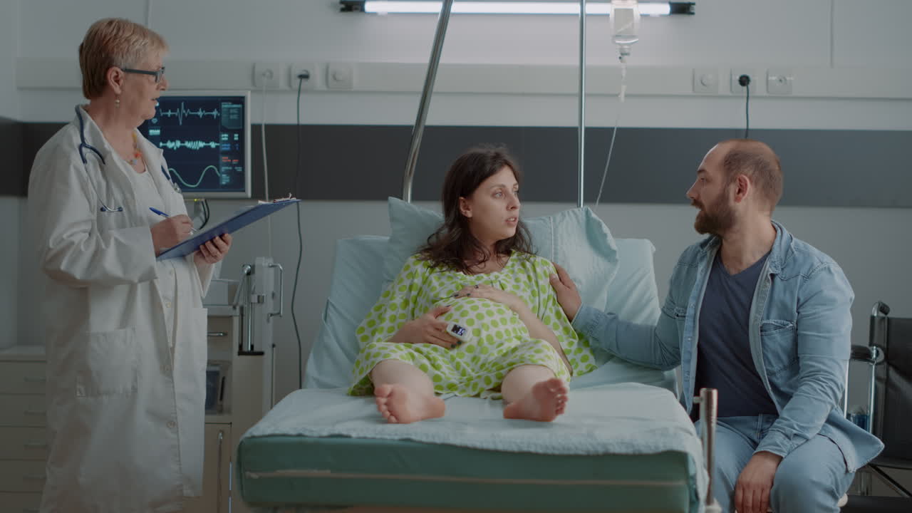 Hospital ward doctor consulting pregnant woman in bed