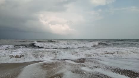 Dolly-En-Cámara-Lenta-Hacia-Atrás-De-Olas-Rompiendo-En-La-Playa,-Día-Nublado