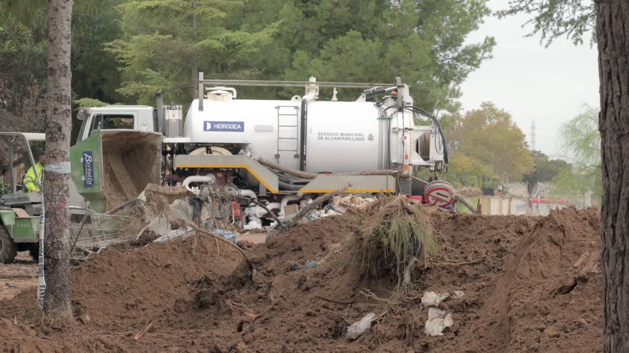 Machinery removing mud and debris from streets after flooding in Valencia