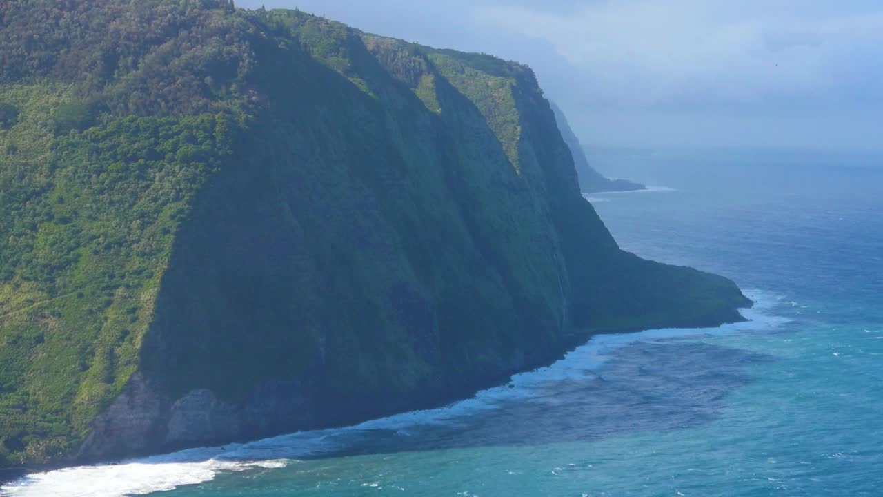 valle de waipio en la isla grande de hawaii en un día ventoso con océano turquesa y acantilados a la sombra de antiguas erupciones volcánicas