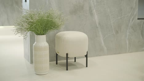 minimalist interior with white vase and upholstered stool