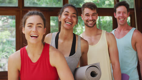 portrait of happy, diverse group of men and women laughing after yoga class in studio
