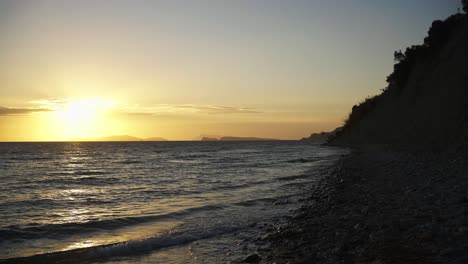 Toma-Panorámica-En-Cámara-Lenta-De-La-Impresionante-Costa-Durante-La-Puesta-De-Sol-En-Arillas,-Corfú,-Grecia