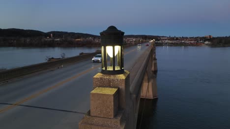 aerial orbit shot of light on top of bridge with driving cars crossing susquehanna river in colombia borough at night