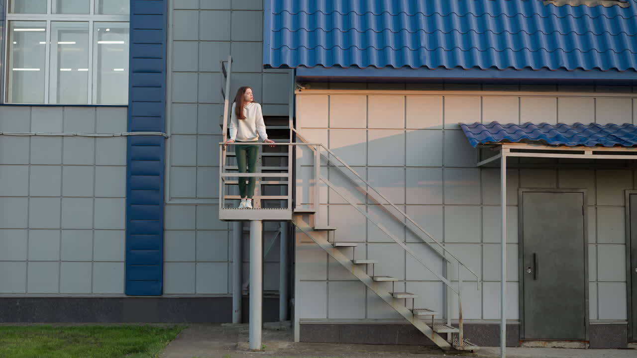 mujer de pie en las escaleras de un edificio. dama reflexiona sobre la depresión de pie sola en la altura. actitud negativa hacia la vida y atmósfera tranquila caminando al atardecer