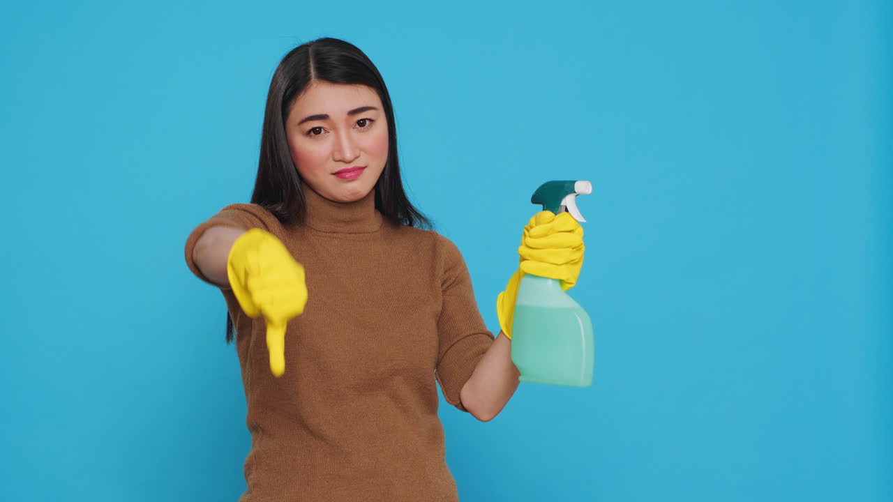 Upset unhappy housekeeper holding hygiene detergent spray doing disapproval sign