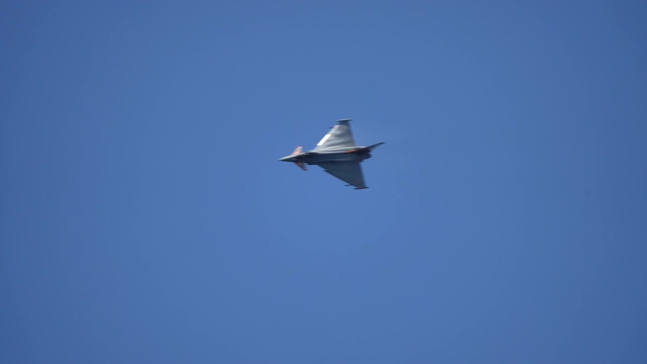 Militært jagerfly drejer i luften med varmeforvrængning fra motoren, filmet i slowmotion.