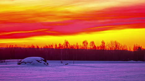 time-lapse of moving red yellow colorful clouds in sky at sunrise in snowy countryside landscape