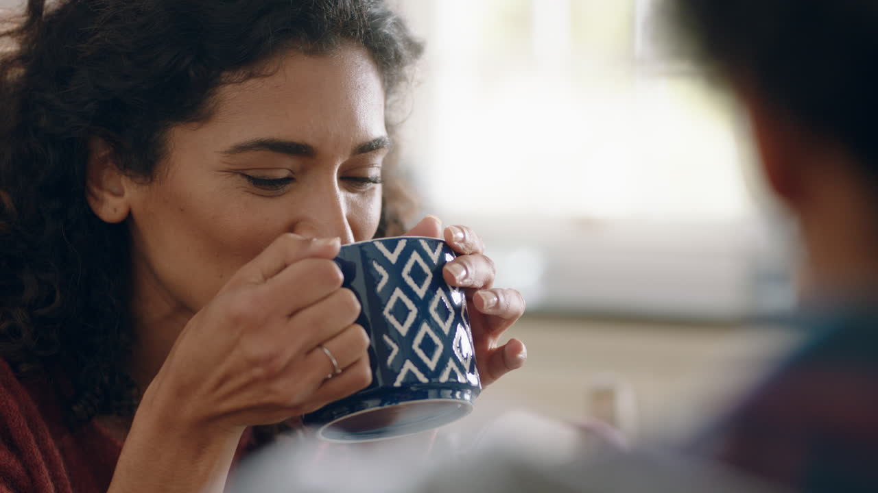 아름다운 행복한 여성이 커피를 마시며 집에서 남편과 채팅하며 아침 식사 때 부 ⁇ 에서 대화를 즐기고 있습니다.