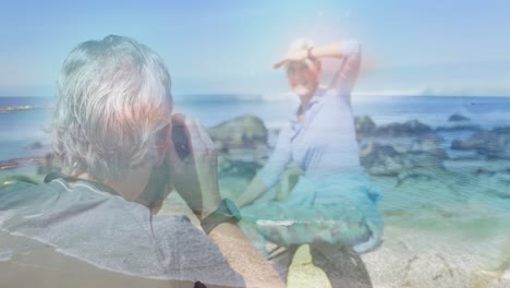 Happy-caucasian-senior-couple-taking-pictures-by-the-coast-over-sea-waves