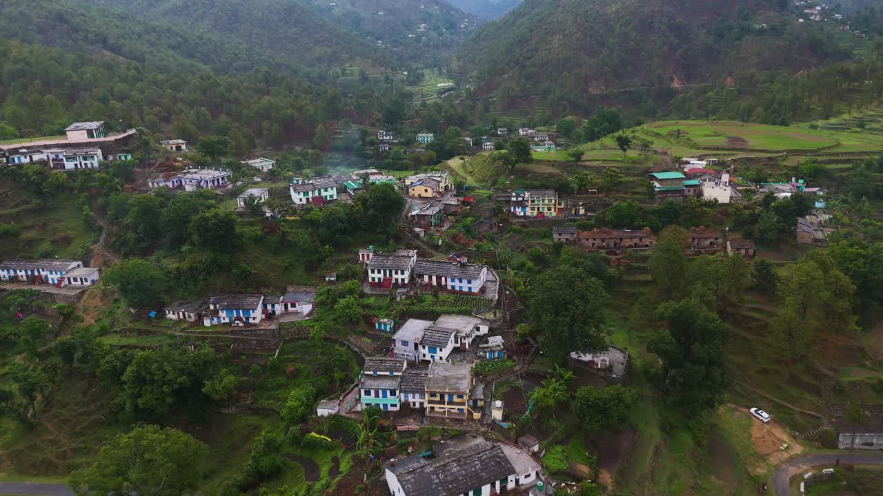Aerial drone shot offering a top-down view of a small village blending into the mountainous landscape.