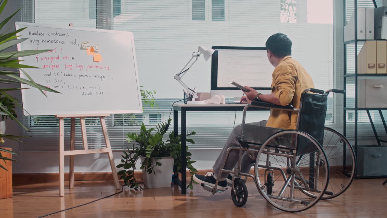 Male Coder in Wheelchair Working on Computer at Office Desk