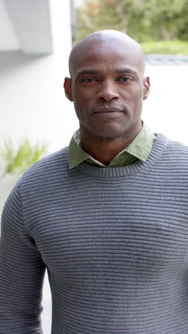 portrait of happy african american man standing and laughing in front of house,slow motion