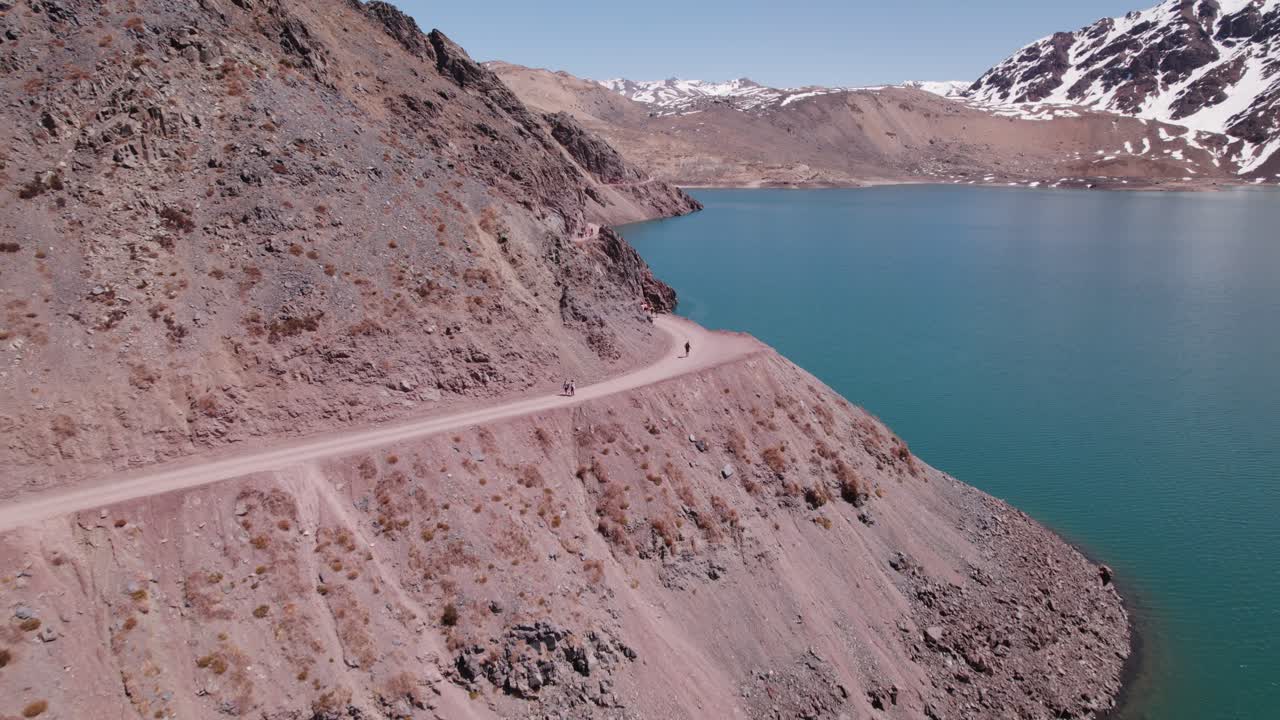 volando sobre un sendero estrecho con gente caminando en el lago el yeso en andes, chile