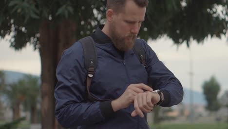 hombre comprobando el reloj inteligente al aire libre