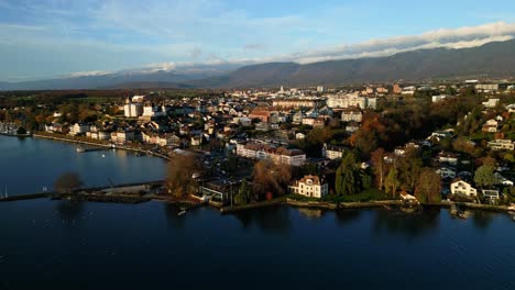 establishing drone shot of nyon cityscape and lake geneva at sunrise in canton of vaud switzerland