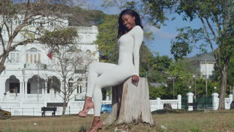 A-young-girl-in-a-white-bodysuit-savors-a-day-in-the-city-with-castles-behind-her-sitting-on-a-tree-trunk