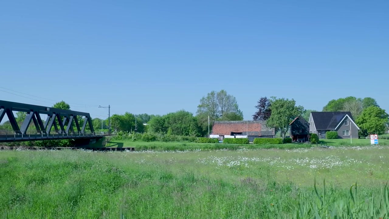 Schilderachtig landelijk landschap met metalen spoorbrug en traditionele boerderij