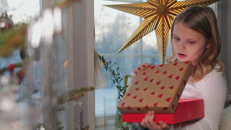 little blonde girl gasps as she opens christmas present