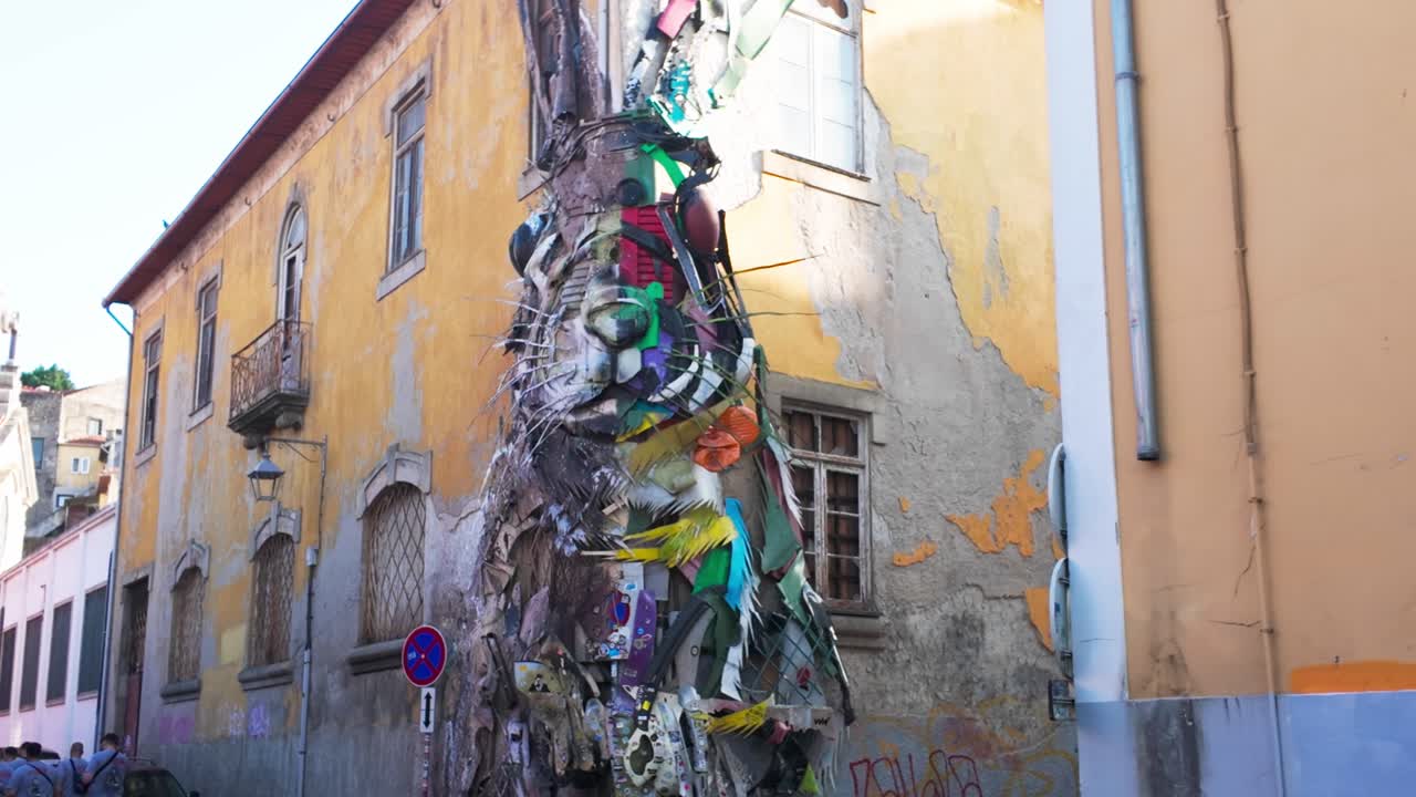 Art installation of a colorful sculpture made of trash between two buildings in Porto, daytime