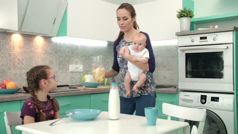 madre con bebé cocinando un desayuno saludable para la hija mayor