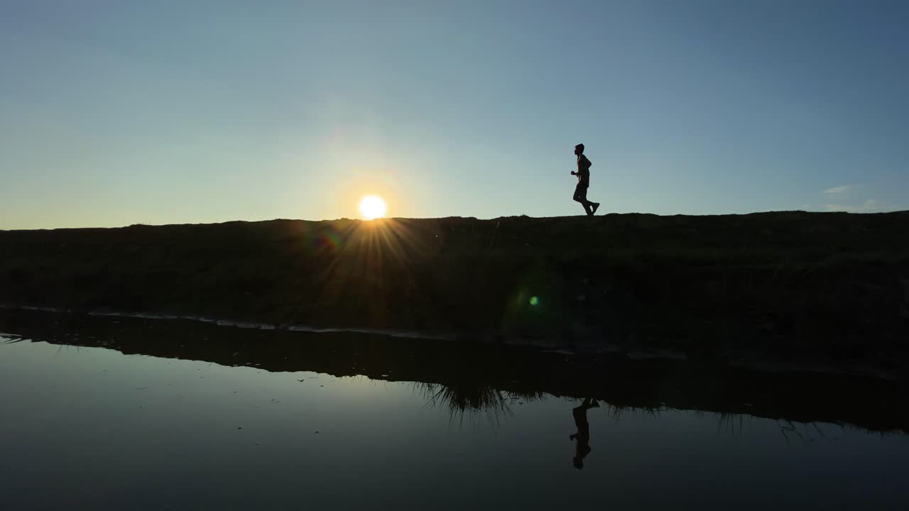 Young man jogging at morning during sunrise beside a lake
