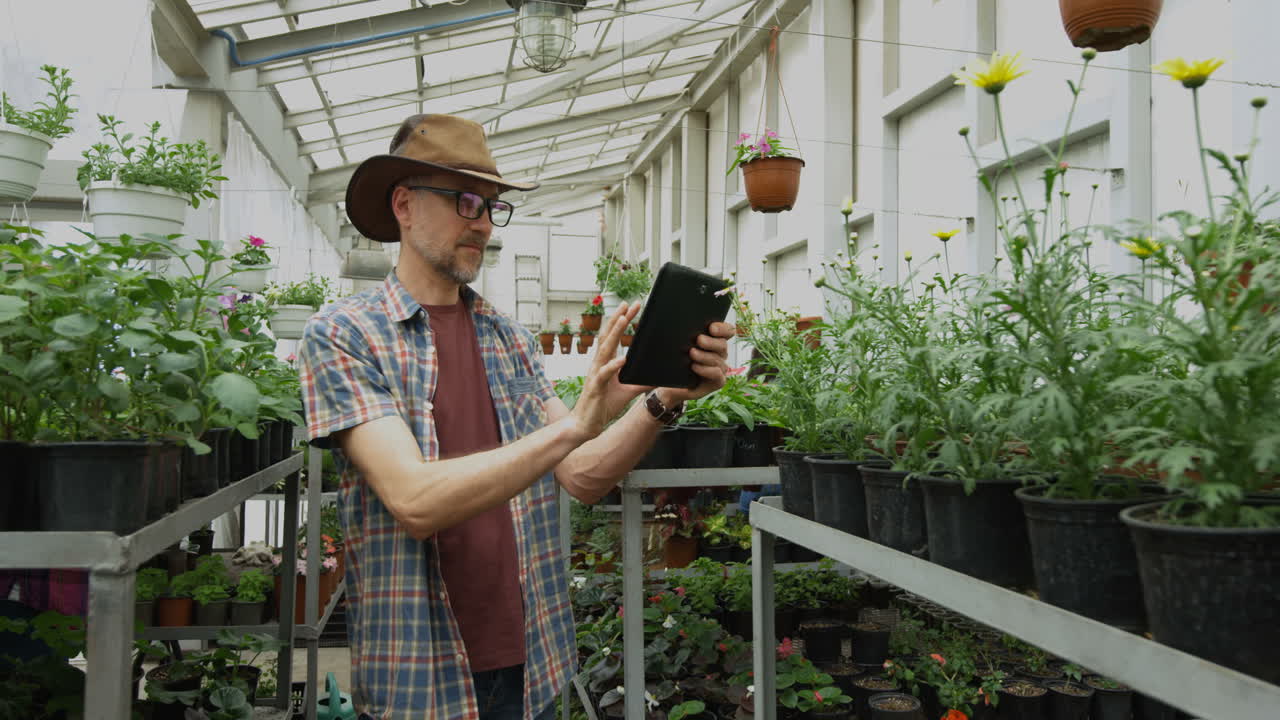 Gardener using tablet in greenhouse