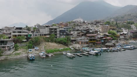 sobrevuelo aéreo del lago de atitlán sobre el agua y luego sobre los edificios y la iglesia en un pueblo que está en la costa