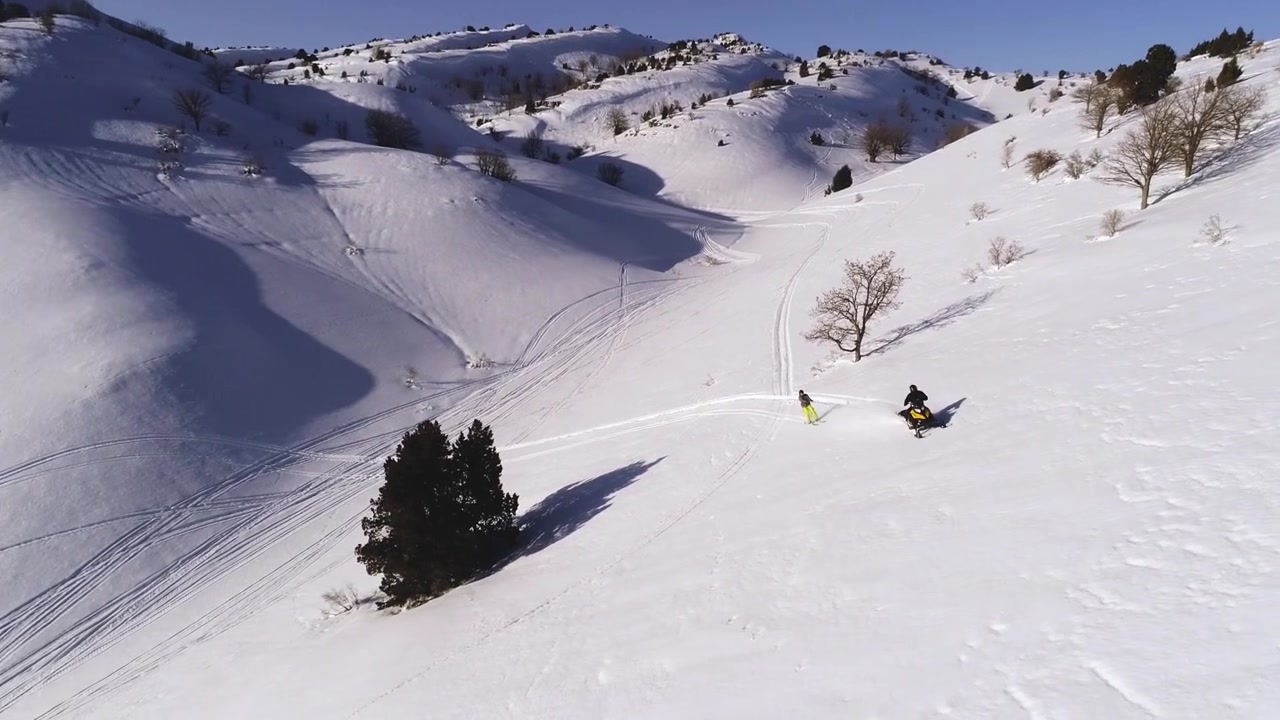 Vista panoramica di motoslitta che traina sciatore su montagna bianca coperta di neve in una giornata di sole, Akoura, Libano, aerea