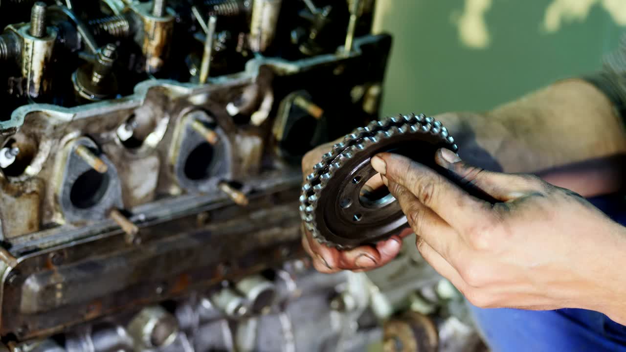 An auto mechanic holds a gearwheel in his hands