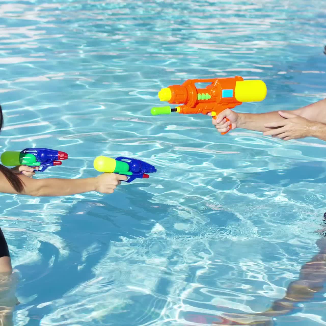 Happy couple shooting off water guns in pool | Premium Stock Video Footage