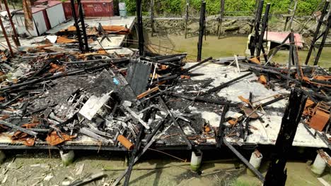 the charred ruins of a riverside building lie next to the rail bridge along river drive in richmond, british columbia, canada - high angle shot