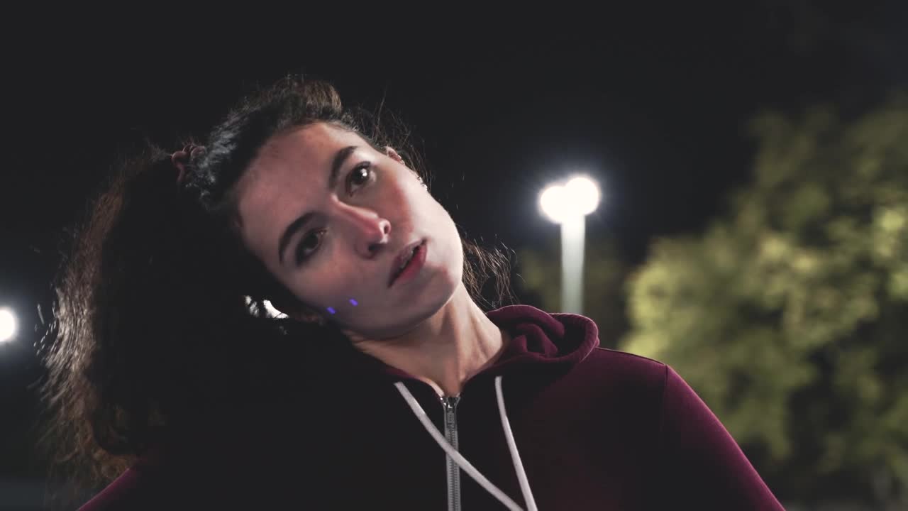 Portrait Of A Sportive Curly Girl Stretching Neck Before Training In The Park At Night 1
