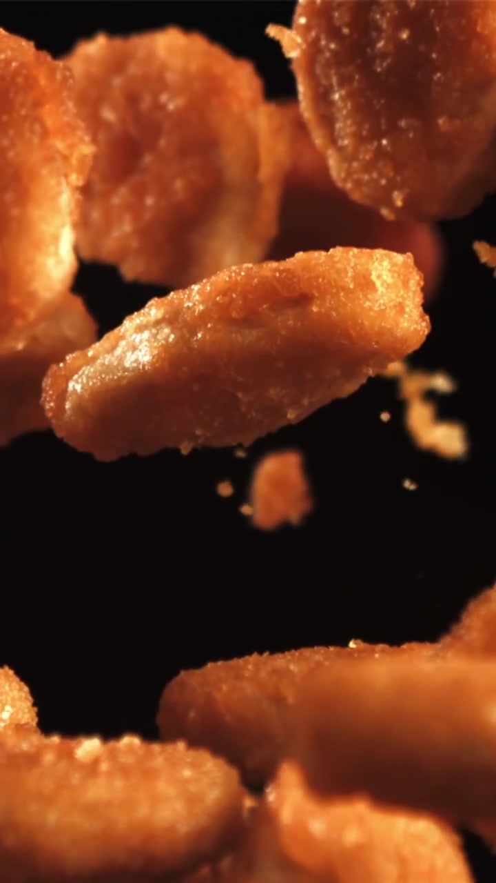 Snack dorati e croccanti che cadono al rallentatore su uno sfondo nero.