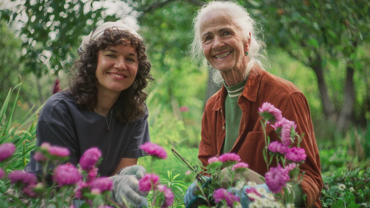 Portrait of Elderly and Young Woman Sitting in Lush Garden among Flowers