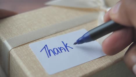 hand writing thank you on a gift tag