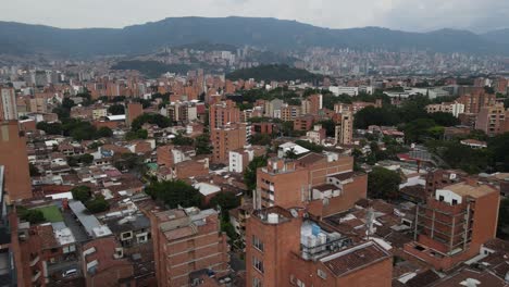Fly-down-toward-building-rooftops-in-a-large-city,-Medellin,-Colombia