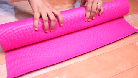 rodando una alfombra de yoga rosada