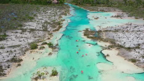 turistas nadando en los rápidos tropicales azules de los rapidos en bacalar méxico en un día soleado, aéreo