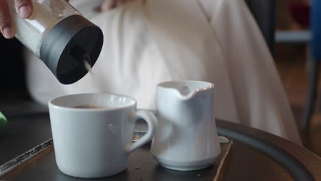 adding sugar to coffee