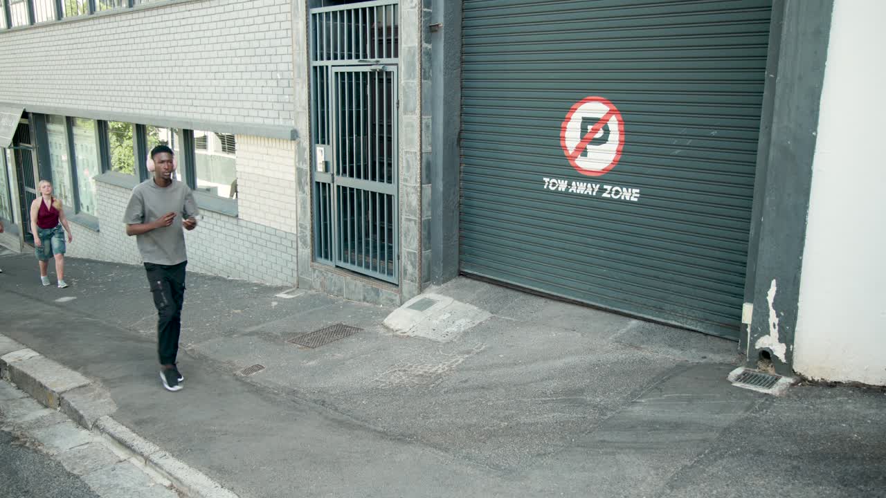 Diverse pedestrians walking after left entry on sloped sidewalk past no parking garage