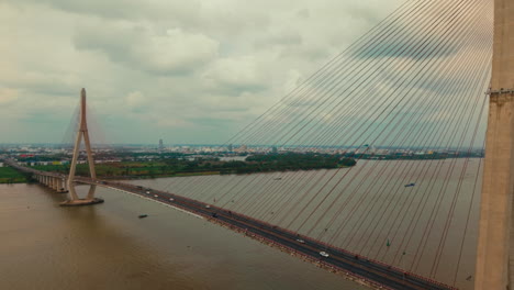 aerial shot of a bridge in vietnam spanning across a river with urban background