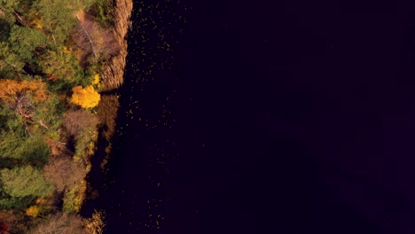 Drone-flyover-along-a-lake-with-autumn-trees-on-the-shore