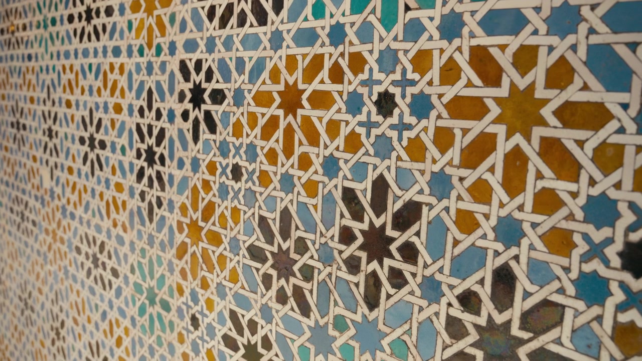 Nahaufnahme von farbenfrohen geometrischen Fliesenmustern im Inneren des Real Alcázar in Sevilla, Spanien, die aufwendiges maurisches Design, Symmetrie und historische Handwerkskunst zeigen.