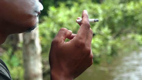 close shot of asian man smoking next to the river