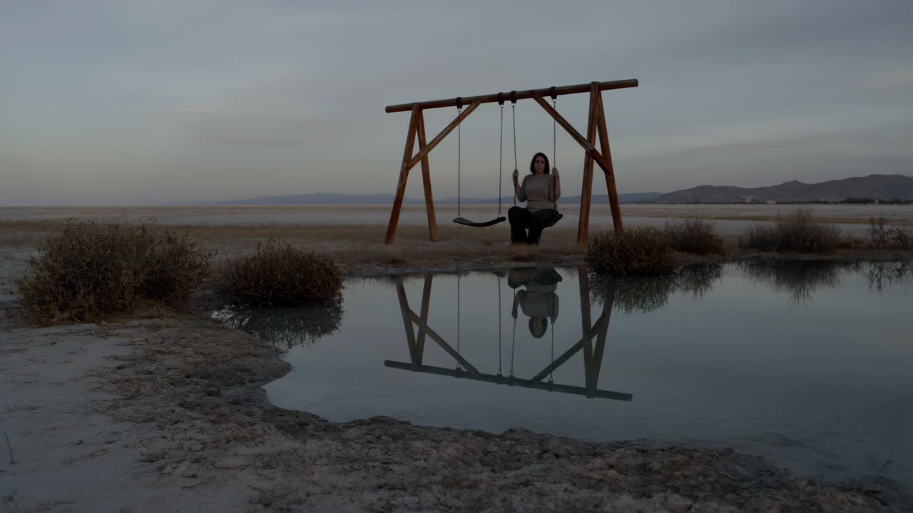 Woman on a swing reflected in calm water