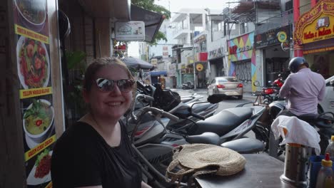 a woman in her 30s sits at a street food restaurant in ho chi minh, vietnam