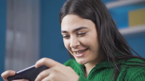 Cheerful-young-woman-happily-playing-phone-at-home.